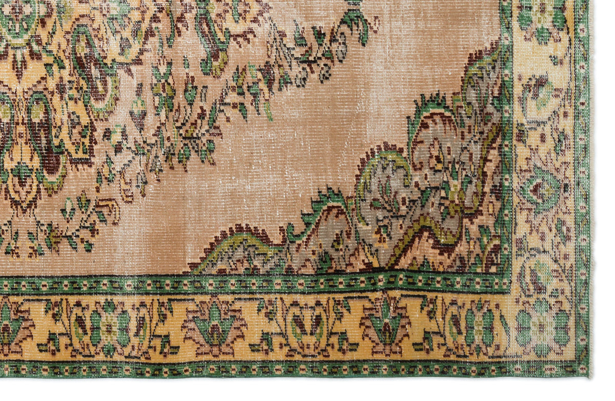 Tan vintage-style rug with a distressed green and brown floral medallion pattern and a decorative border.