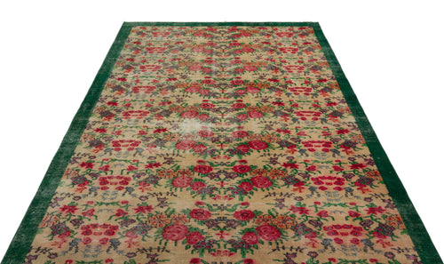 Load image 1 in gallery view. Beige vintage-style rug with a distressed floral pattern in red, green, and purple, featuring a solid green border.