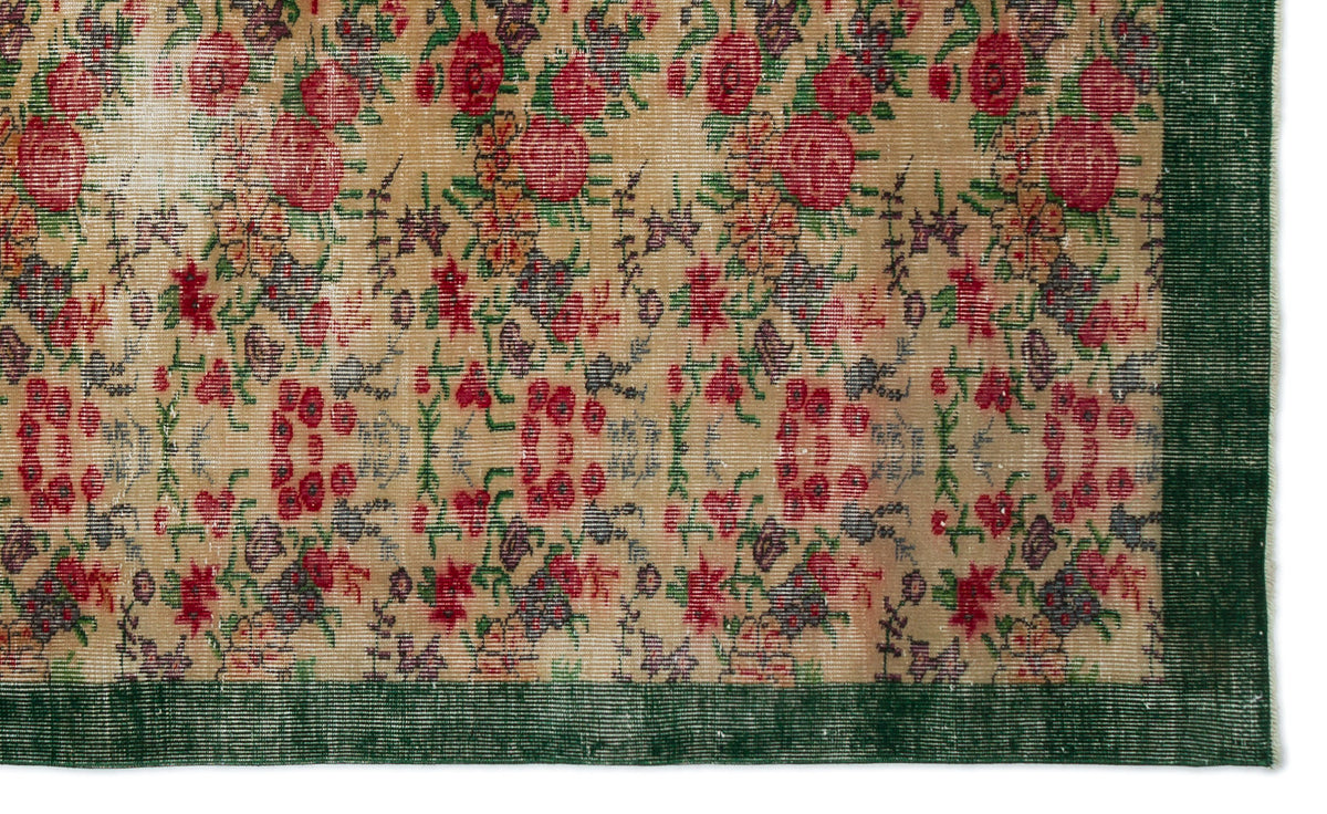Tan vintage-style rug with a distressed floral pattern in red, green, and purple, featuring a solid dark green border.