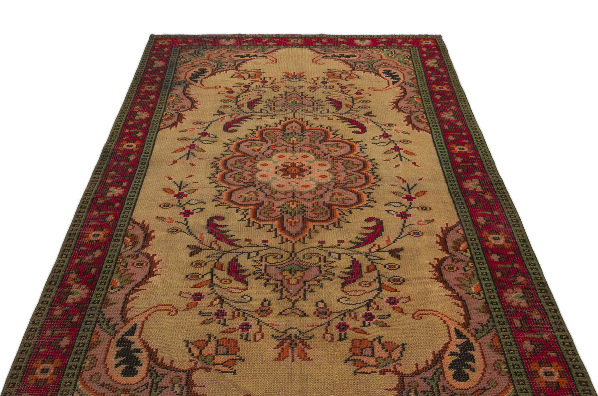 Beige traditional rug with a central floral medallion, intricate botanical motifs, and a red and green border.