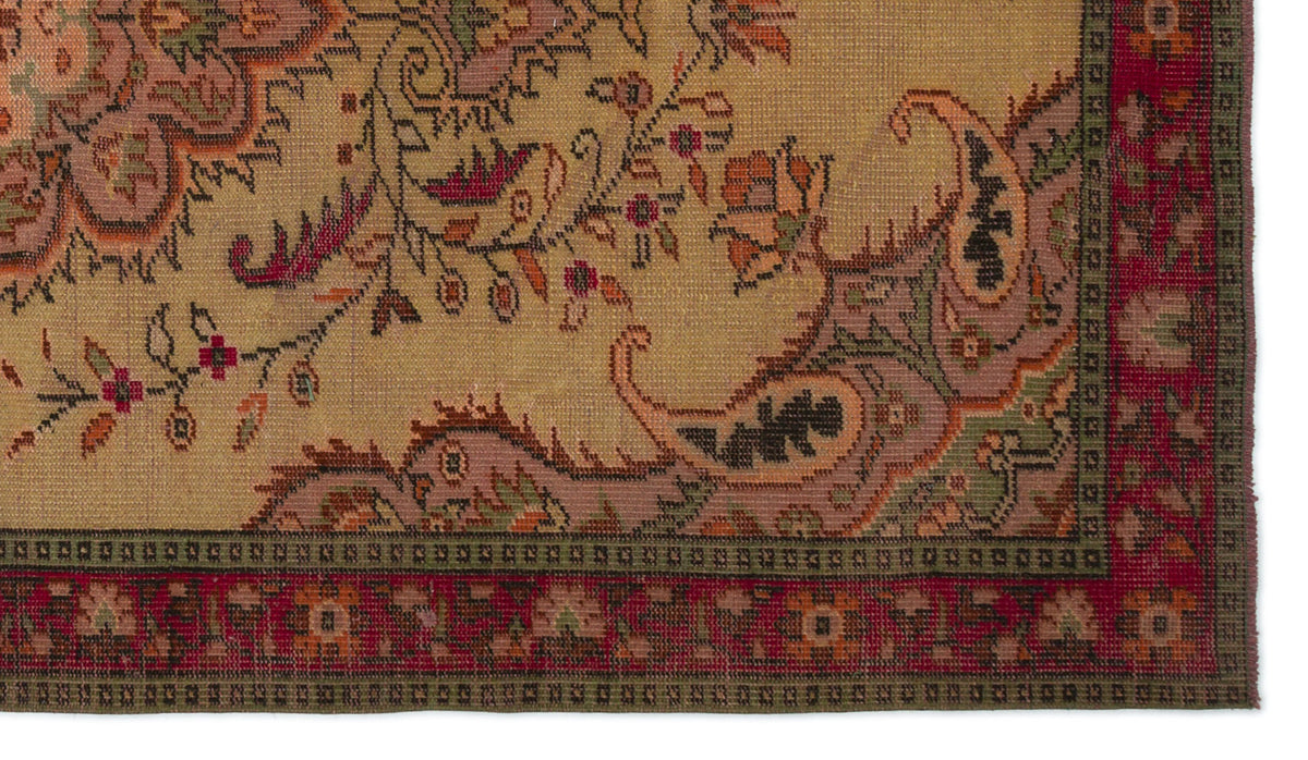 Tan traditional rug with a floral and paisley pattern in muted red, green, and mauve, featuring a decorative border.