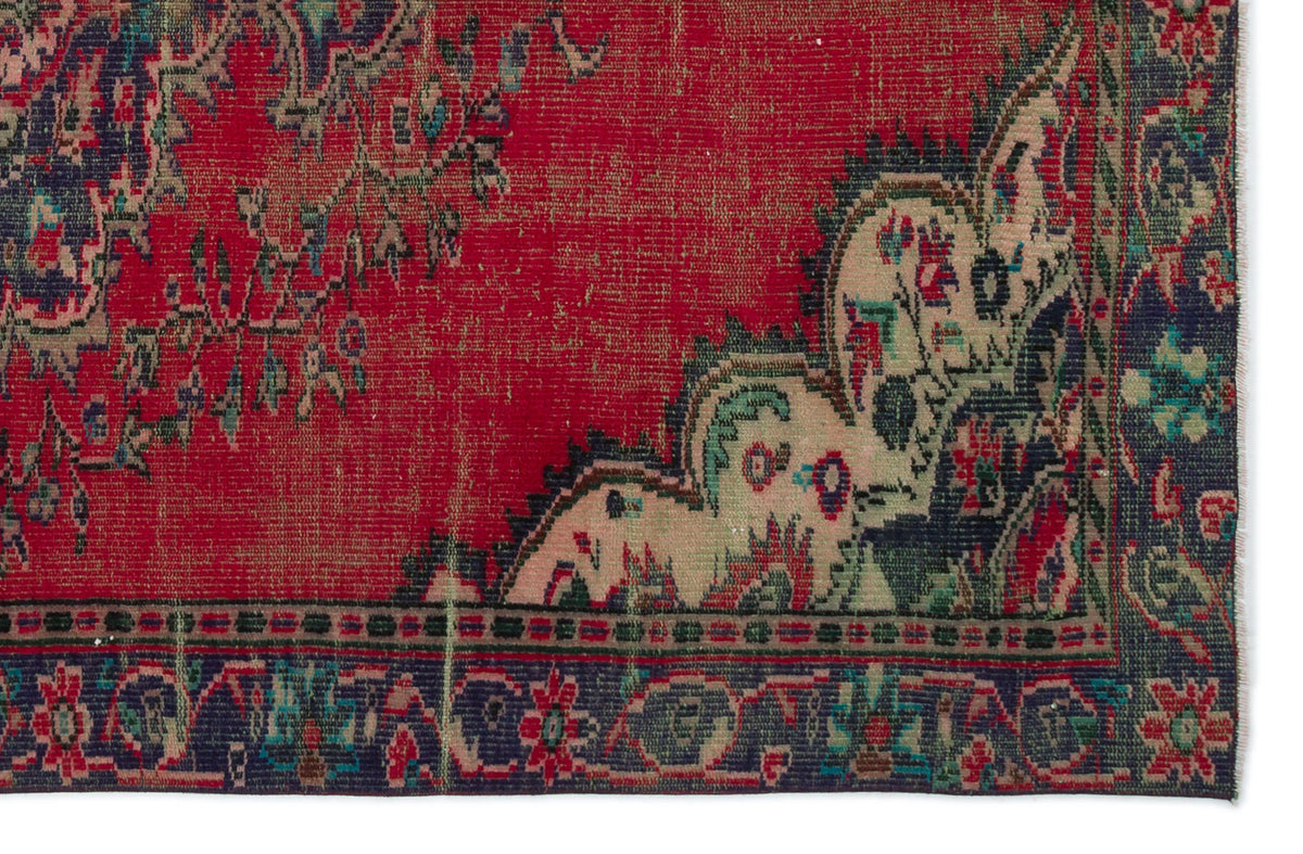 Distressed red vintage-style rug with a dark blue border and intricate floral medallion pattern.