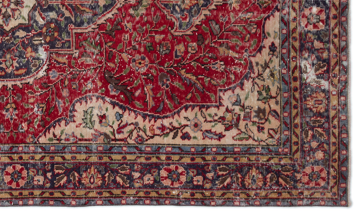 Distressed traditional Persian-style rug with a red floral medallion, cream accents, and a dark blue geometric border.