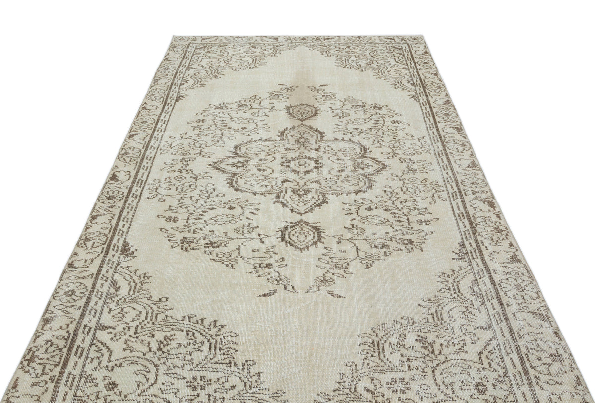 Beige and brown vintage-style rug with a central floral medallion and ornate border on a white background.