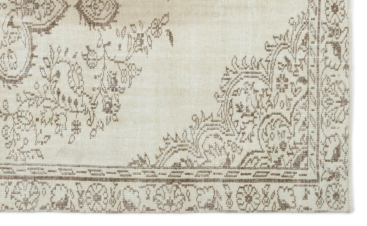 Beige rug with a distressed brown floral medallion pattern and a decorative border.
