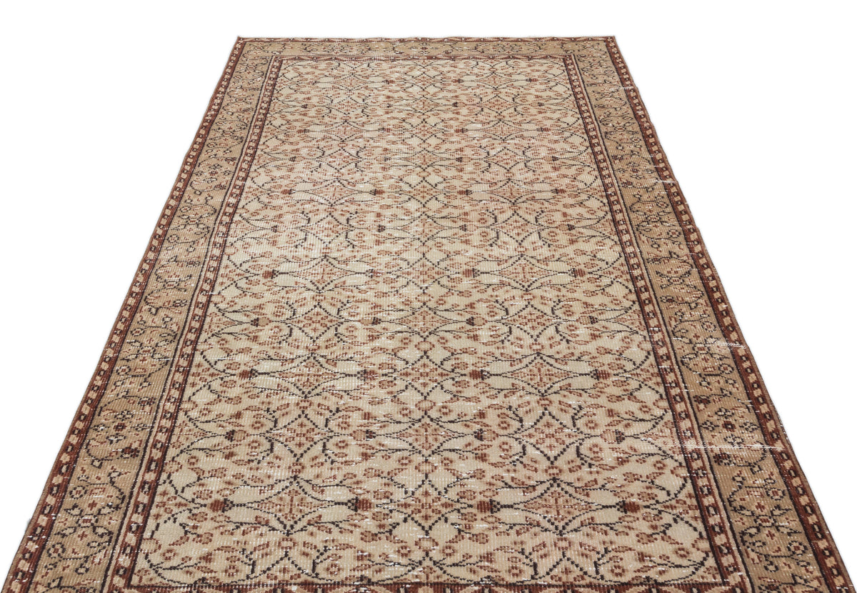 Beige and brown vintage-style rug with a repeating geometric floral lattice pattern and a decorative border.