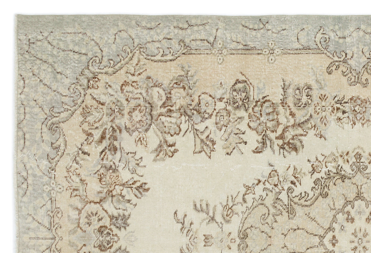 Distressed beige and light blue rug with a faded floral medallion pattern.