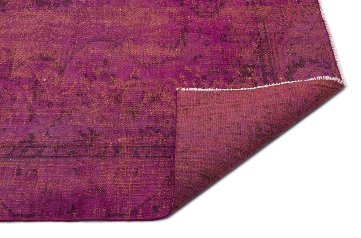 Magenta distressed vintage-style rug with a faded dark purple floral pattern and a folded corner on a white background.