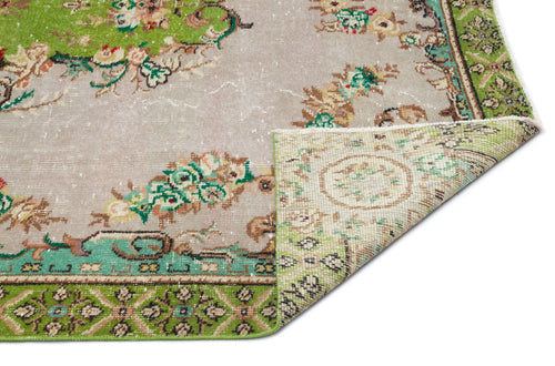 Load image 1 in gallery view. Distressed beige and green rug with a floral medallion pattern and a folded corner showing the woven backing.