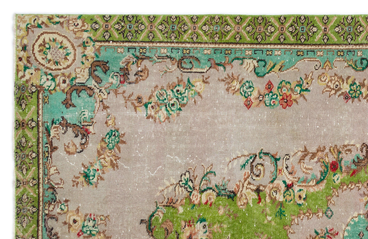 Distressed beige rug with green and teal floral borders and ornate botanical motifs on a neutral field.