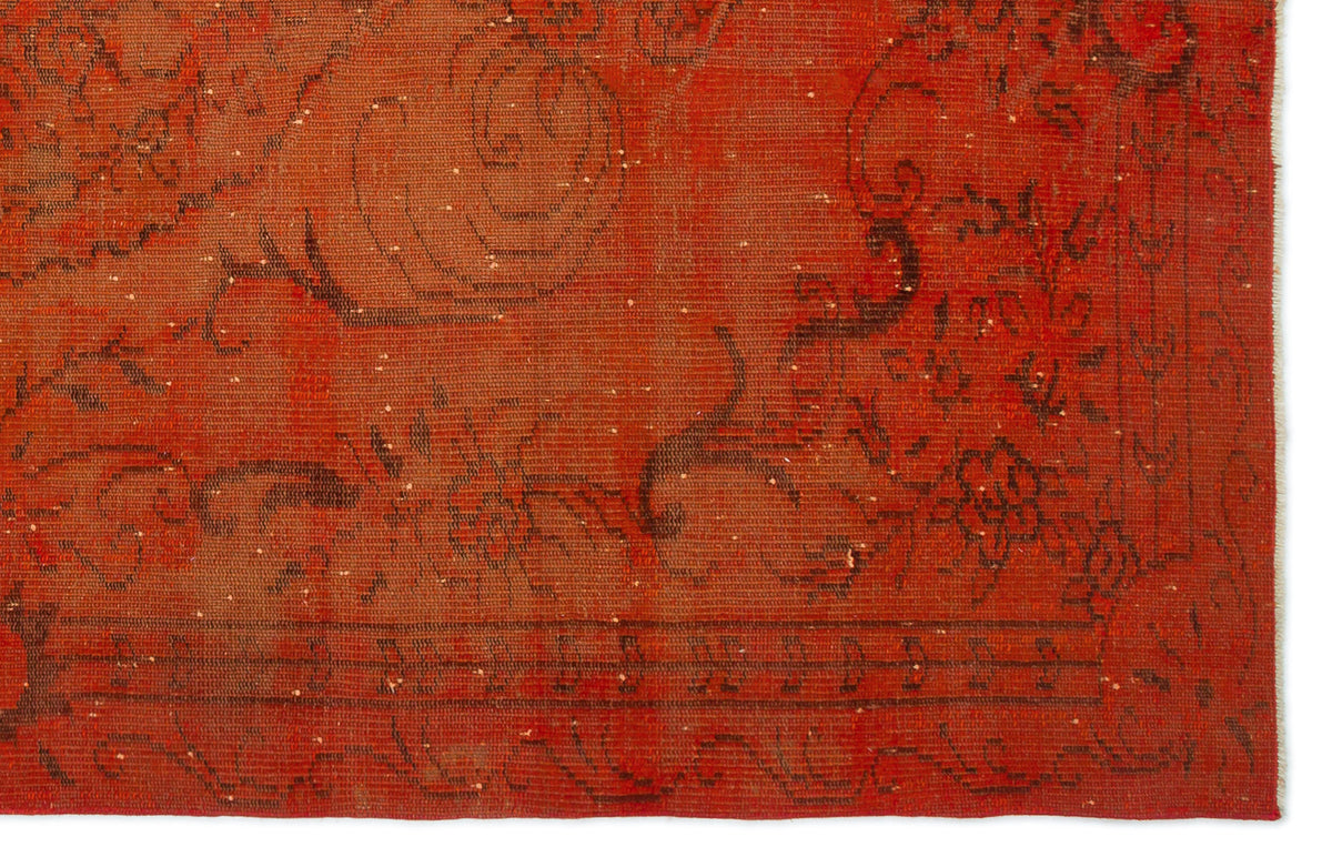 Distressed terracotta rug with a faded black floral pattern and a linear border.