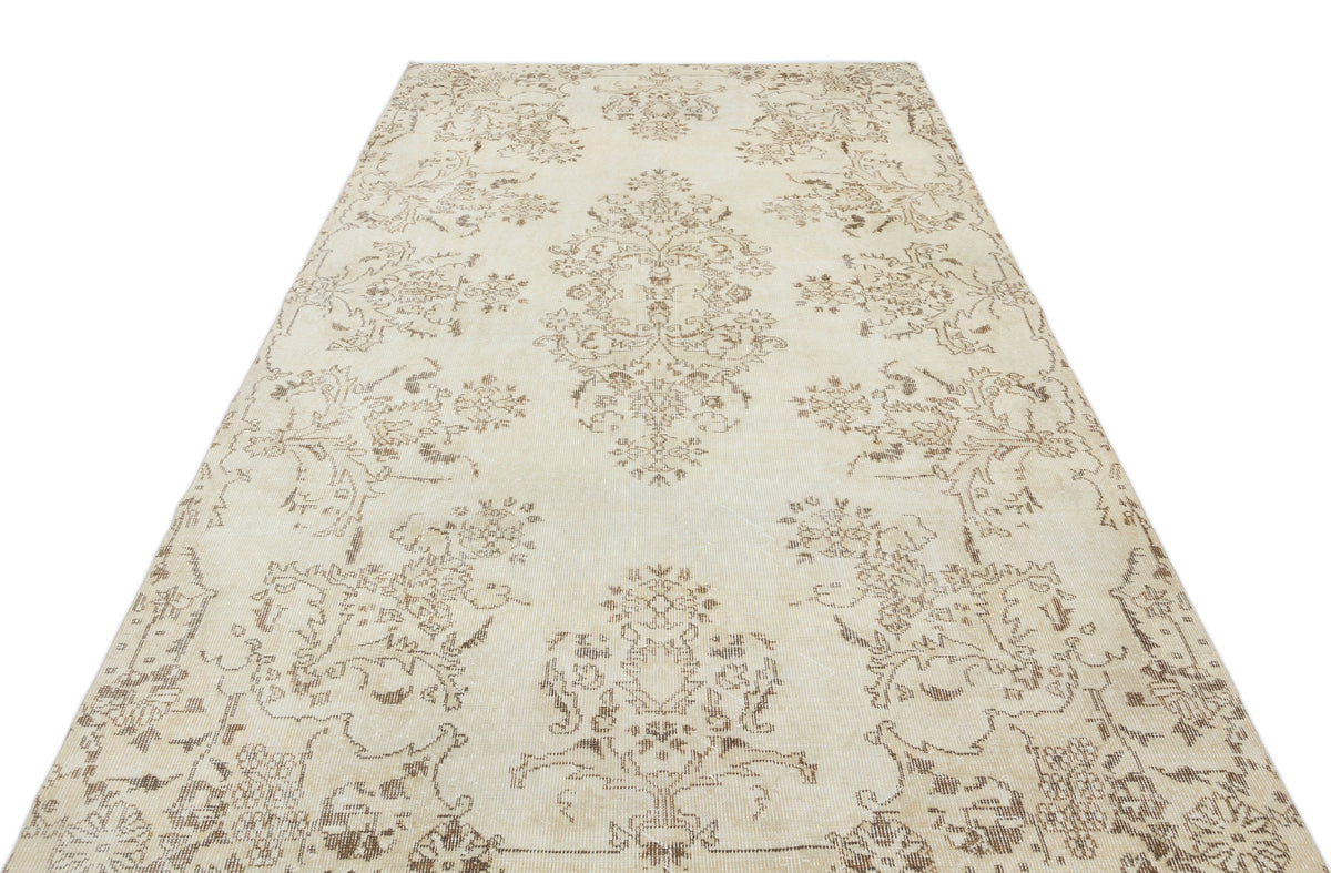 Cream and beige vintage-style rug with a distressed floral medallion pattern on a white background.