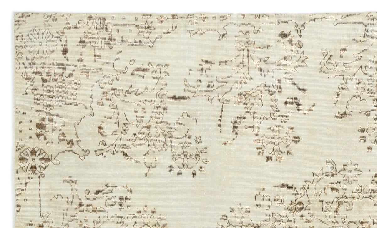 Cream rug with a distressed brown floral and vine pattern.