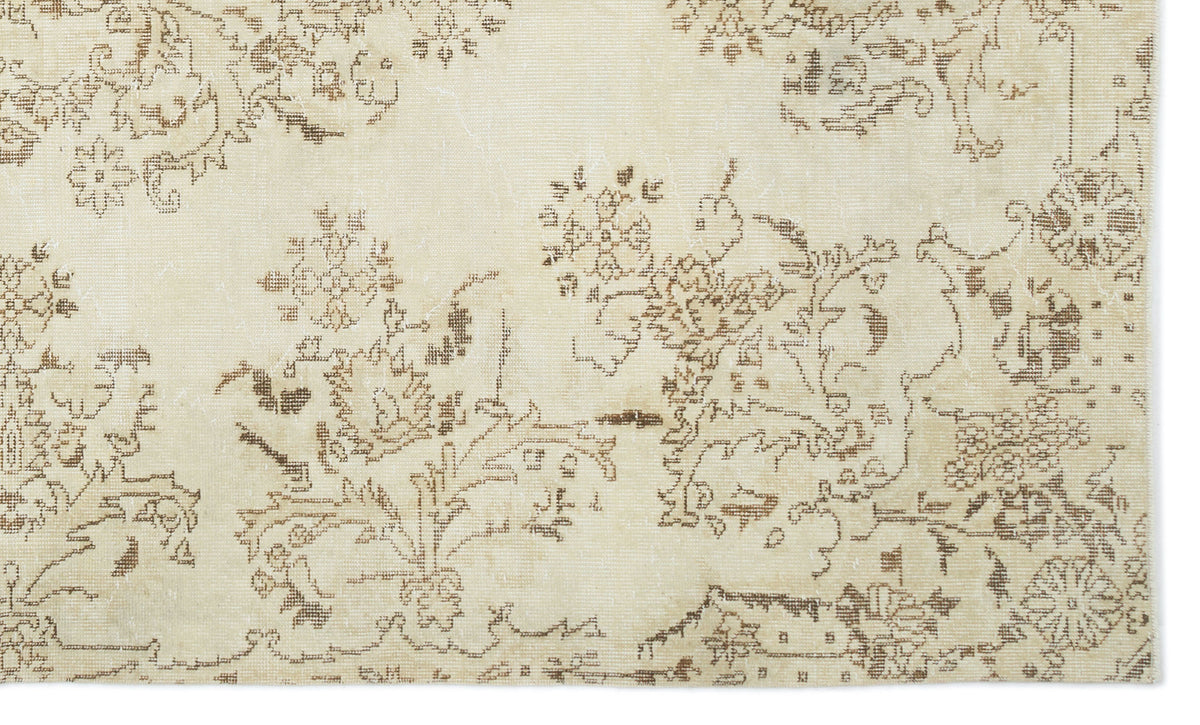Cream rug with a distressed brown floral and vine pattern.