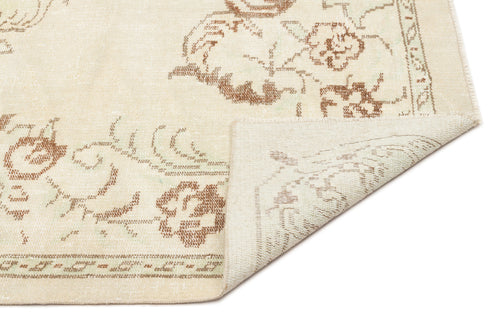 Load image 1 in gallery view. Cream rug with a distressed brown floral pattern and a folded corner showing the woven backing.