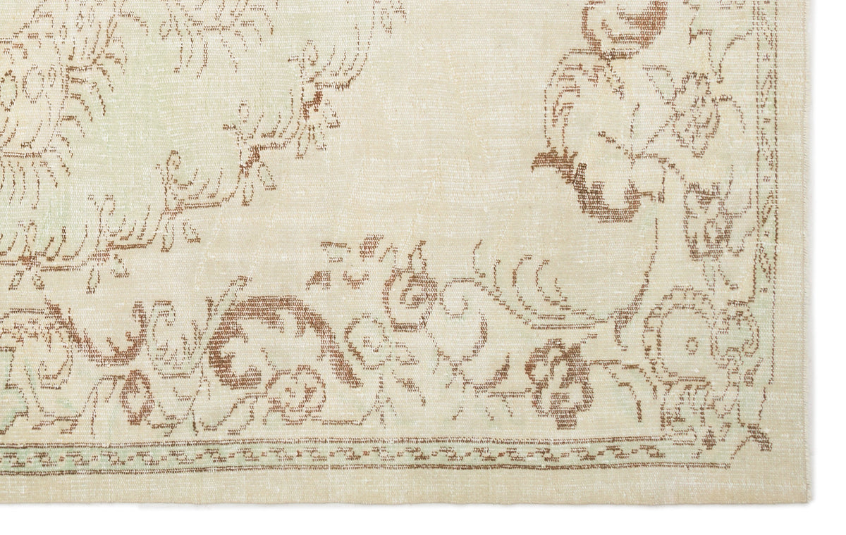 Cream rug with a distressed brown floral medallion pattern and a decorative border.