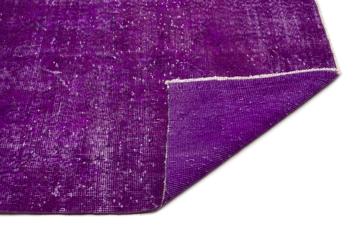 Deep purple distressed vintage-style rug with a folded corner revealing the woven backing on a white background.