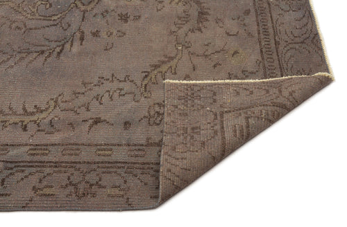Load image 1 in gallery view. Dark brown distressed rug with a faded traditional floral medallion pattern and a folded corner showing the underside.