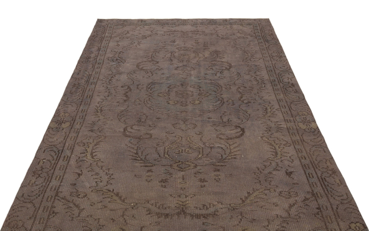 Dark brown vintage-style rug with a faded central medallion and ornate border pattern on a white background.
