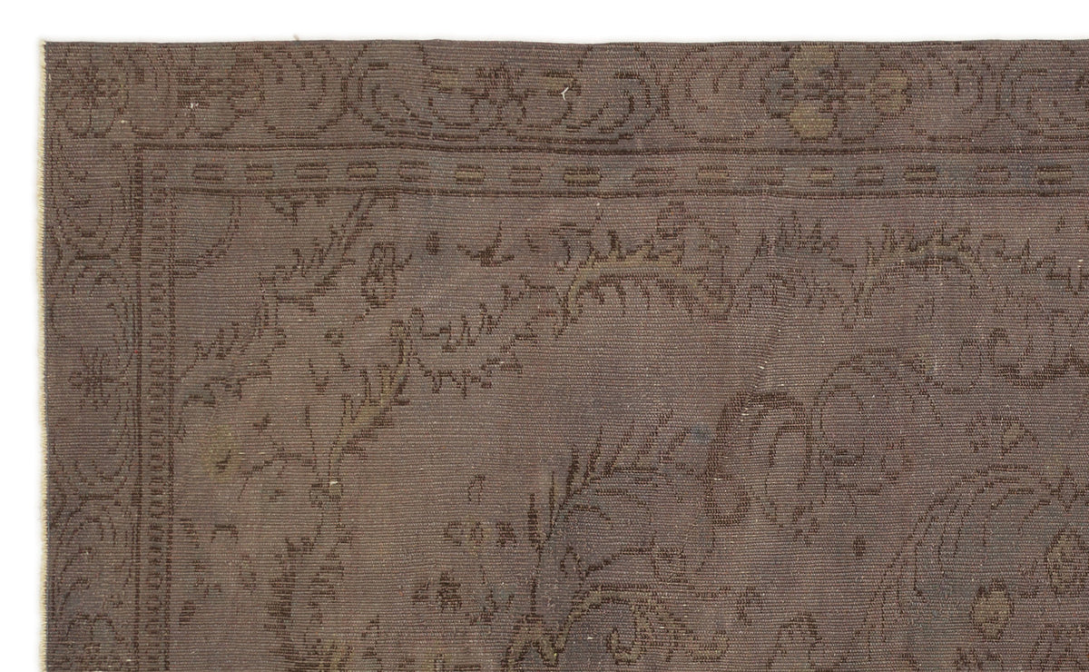 Dark brown rug with a tonal, low-contrast floral medallion pattern and a decorative border.