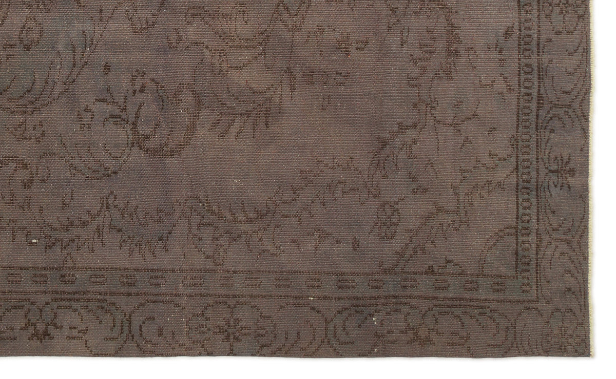 Dark brown flatweave rug with a subtle, tonal floral medallion pattern and a decorative border.