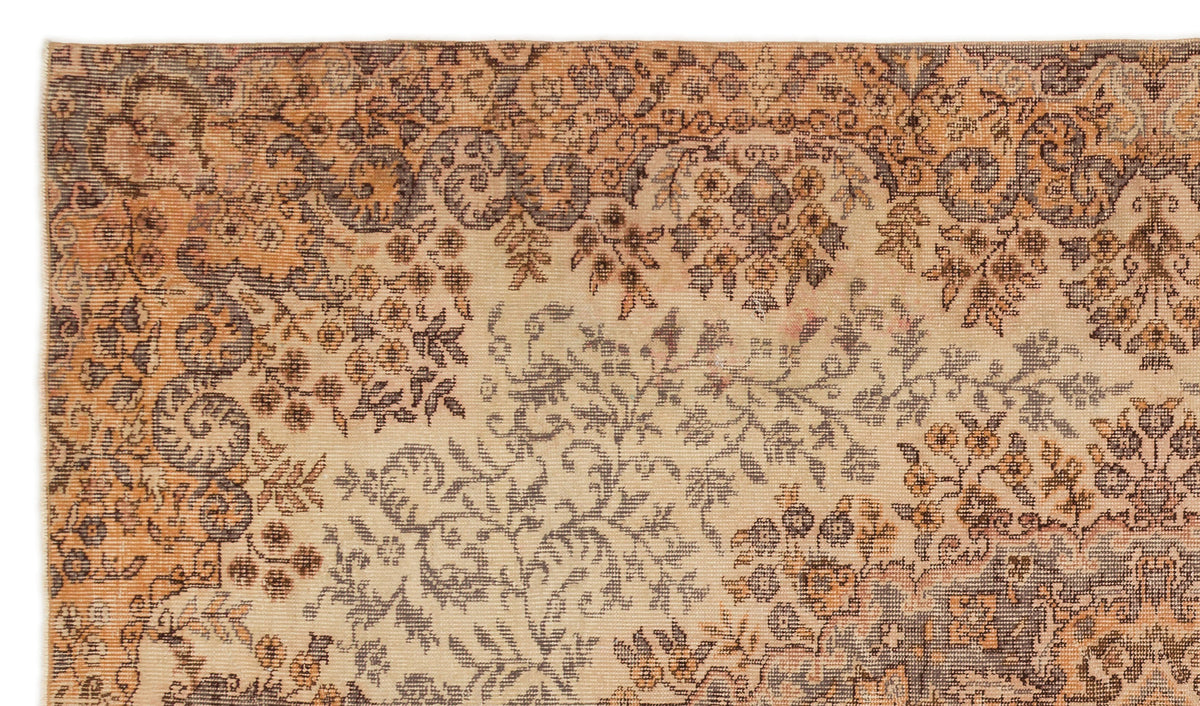 Beige, orange, and charcoal vintage-style rug with a dense, distressed floral and vine pattern.