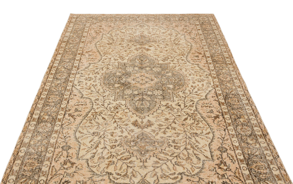 Beige and brown vintage-style rug with a distressed floral medallion pattern and ornate border.