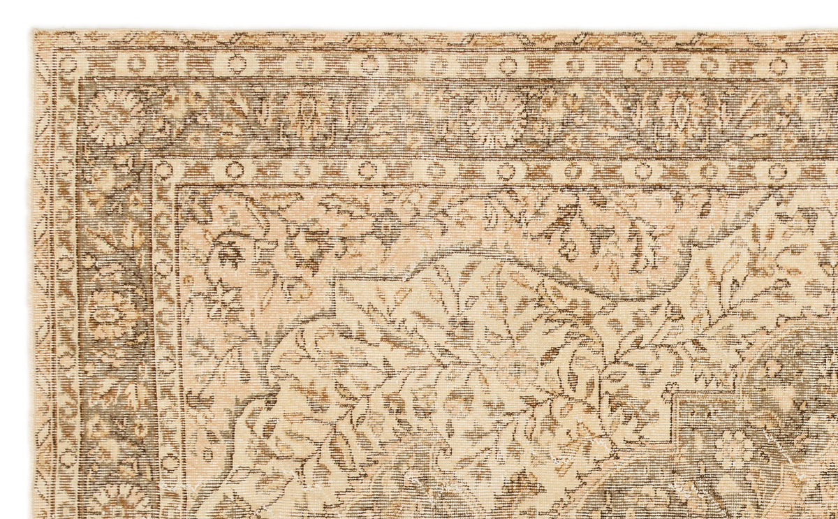 Beige and brown traditional rug with a distressed floral medallion pattern and geometric border.