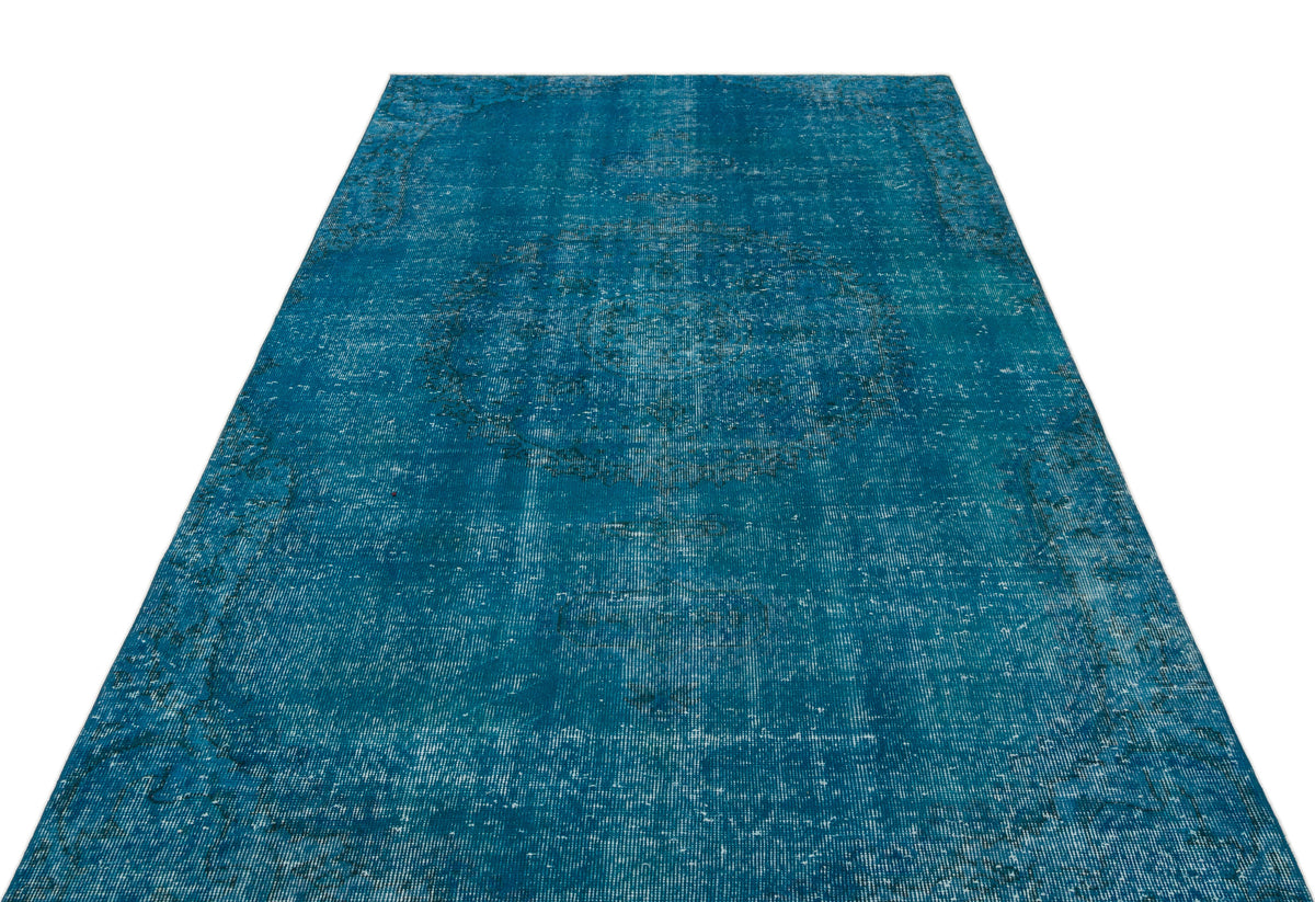 Teal distressed area rug with a faded central medallion and traditional border pattern on a white background.
