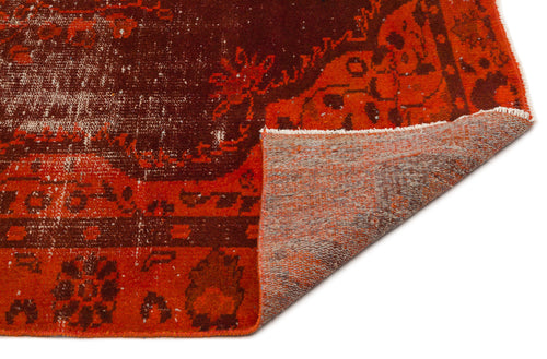 Load image 1 in gallery view. Distressed rust and dark brown traditional rug with a floral medallion pattern, shown with a corner folded over.