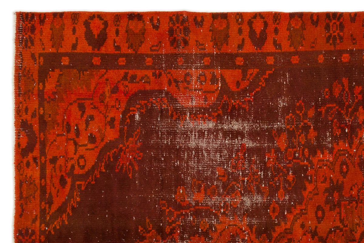 Distressed rust and dark brown rug with a traditional floral medallion pattern and a geometric border.