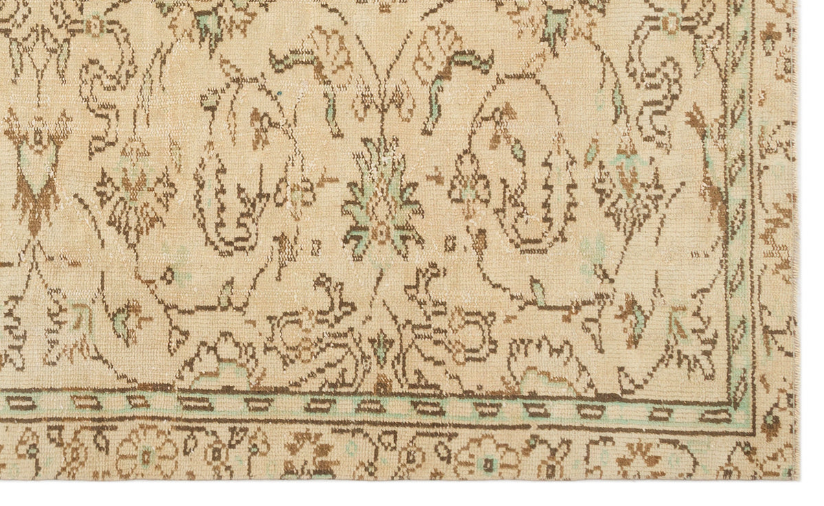 Beige rug with a distressed brown and mint green floral medallion pattern and a geometric border.