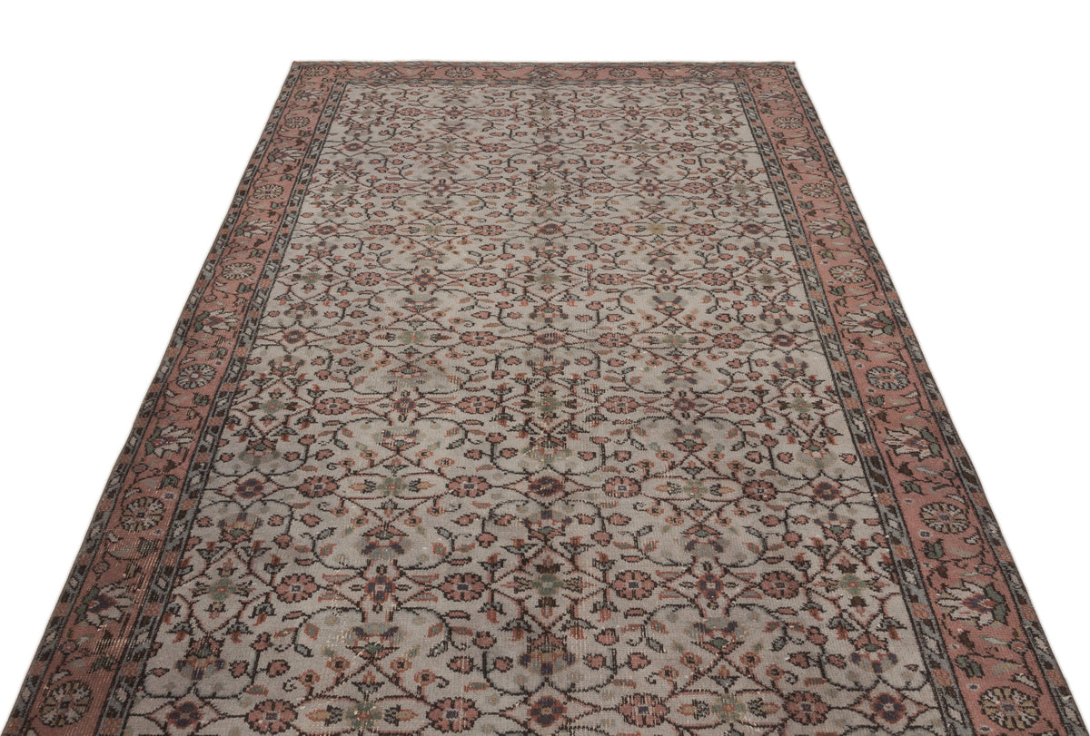 Beige and dusty rose vintage-style rug with an all-over floral vine pattern and a wide decorative border.