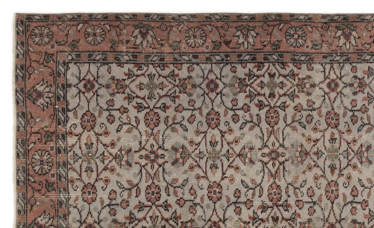 Muted pink and grey traditional rug with a repeating floral medallion pattern and a decorative border.