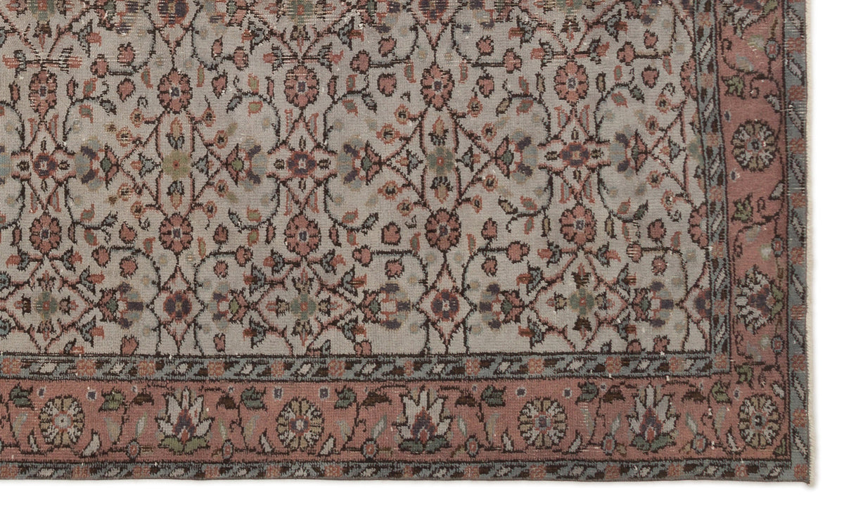 Beige rug with a muted floral vine pattern in pink, sage green, and charcoal, featuring a wide decorative floral border.