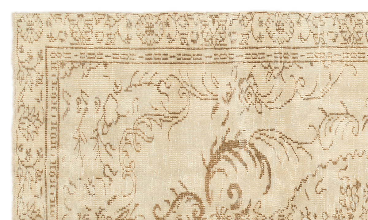 Beige and tan rug with a distressed traditional floral medallion pattern and a geometric border.