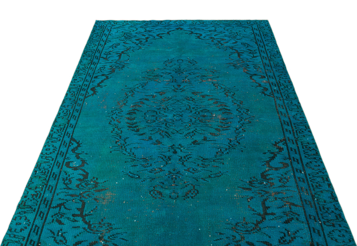 Teal and black distressed rug with a central floral medallion and ornate border pattern on a white background.