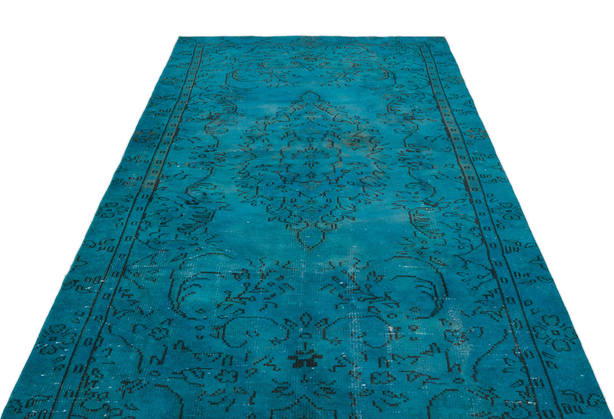 Turquoise distressed rug with a black traditional floral medallion pattern on a white background.