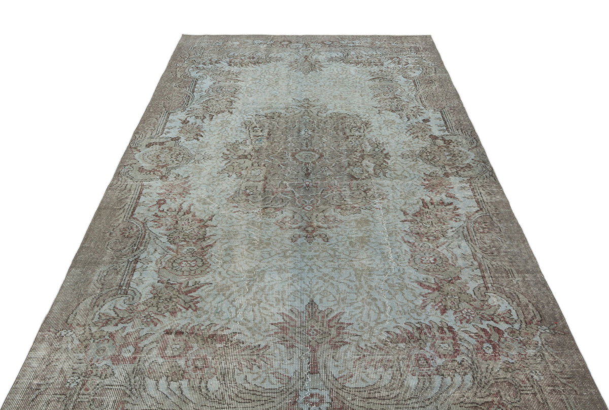 Distressed light blue and brown vintage-style rug with a central floral medallion and ornate border.