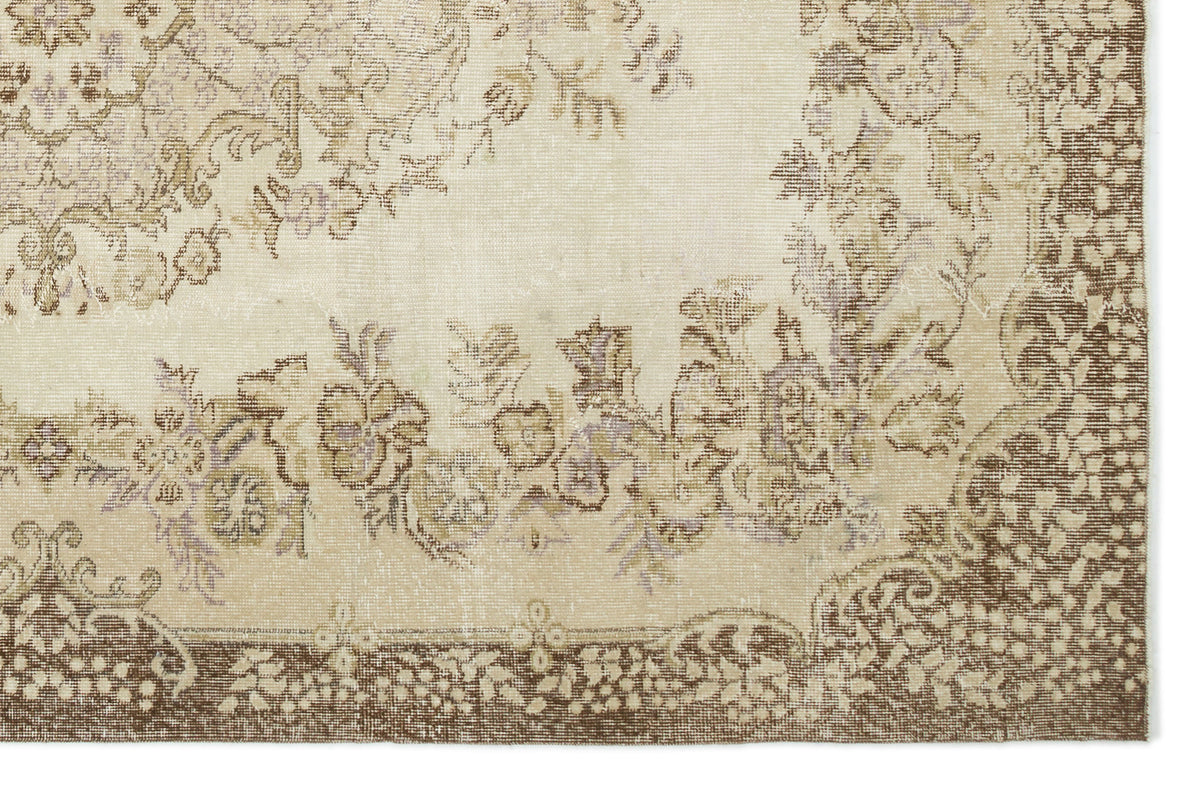 Beige and brown vintage-style rug with a faded floral medallion pattern and a decorative border.