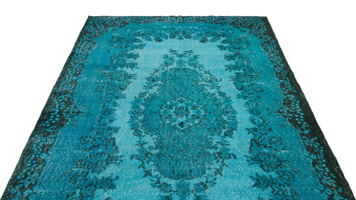 Turquoise and black distressed rug with a central floral medallion and ornate border on a white background.