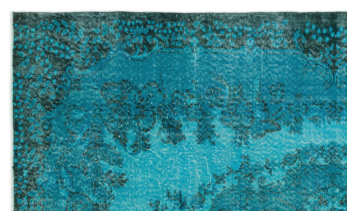 Teal and black distressed rug with a faded floral medallion pattern.
