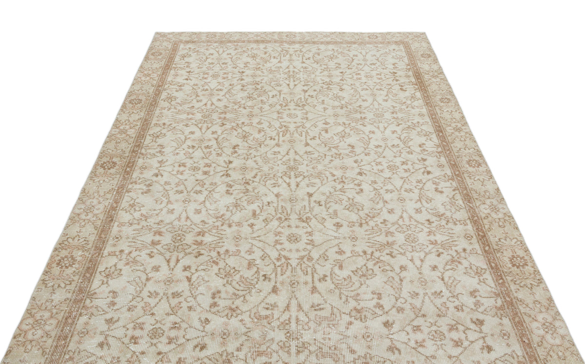 Beige and cream vintage-style rug with a symmetrical floral medallion pattern and a decorative border.