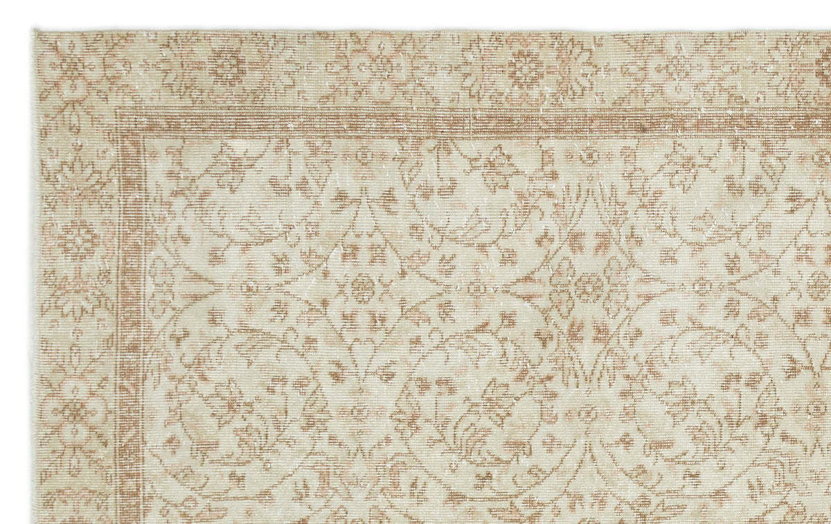 Beige and cream rug with a distressed floral medallion pattern and a decorative border.