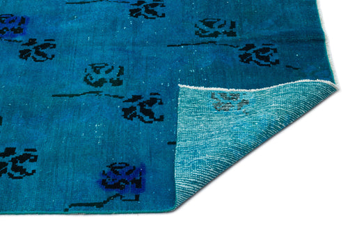 Load image 1 in gallery view. Bright blue rug with a distressed black floral pattern and a folded corner revealing a light blue woven backing.