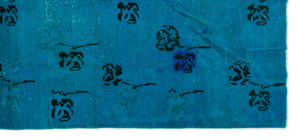 Bright blue rug with a distressed texture and scattered black floral motifs.