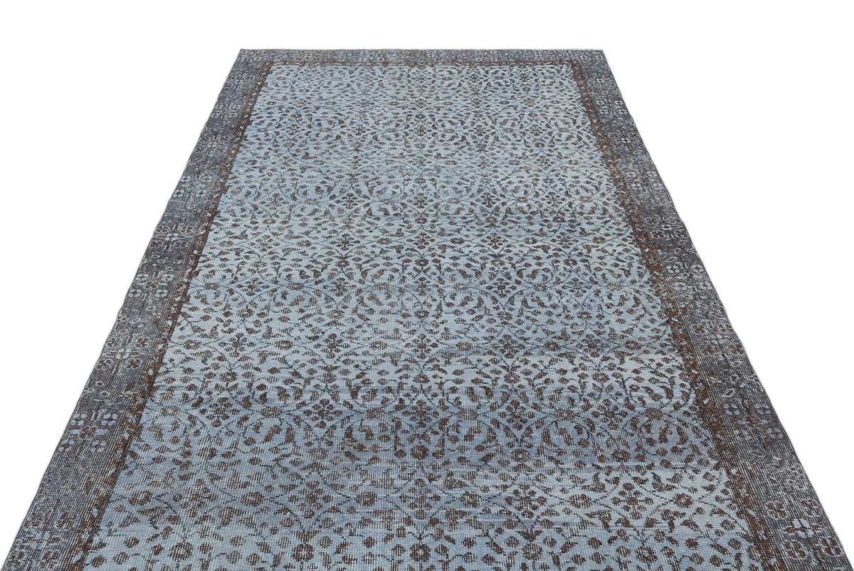 Light blue and dark brown vintage-style rug with an intricate floral medallion pattern and a wide decorative border.