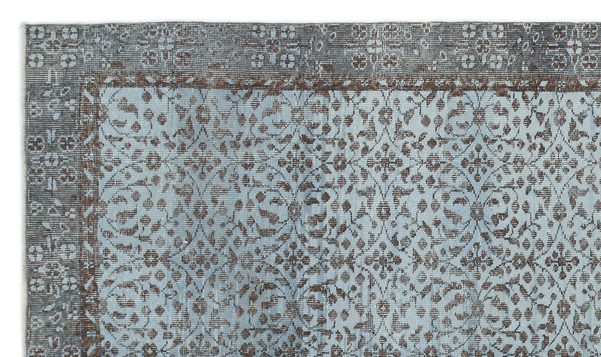 Light blue and brown rug with a distressed floral medallion pattern and a wide decorative border.