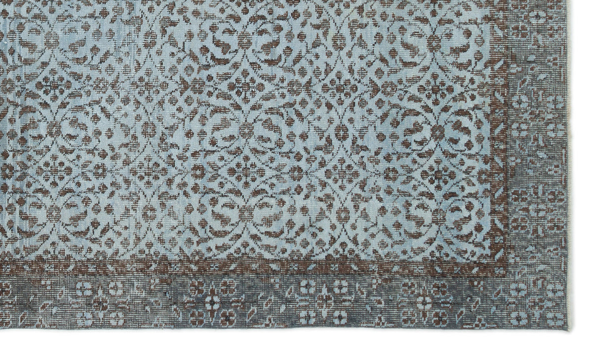 Light blue and brown rug with a distressed traditional floral medallion pattern and a wide decorative border.