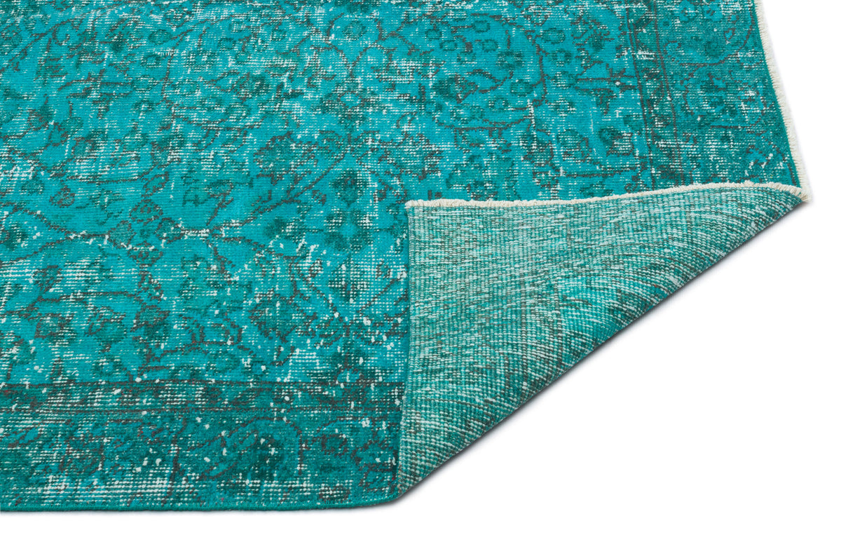 Teal and charcoal distressed traditional rug with a folded corner showing the woven backing.